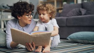 a woman reading a book to a child on the floor